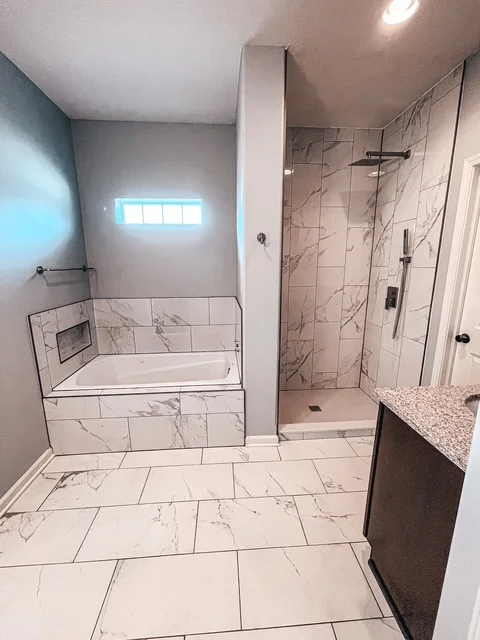 Marble tile bathroom with walk-in shower, quartz vanity, and frameless glass enclosure