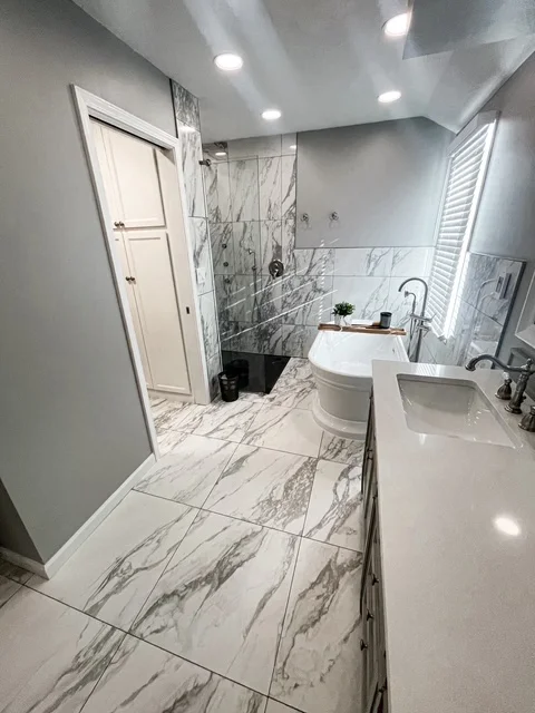Marble tile bathroom with walk-in shower, dual vanity, and marble flooring