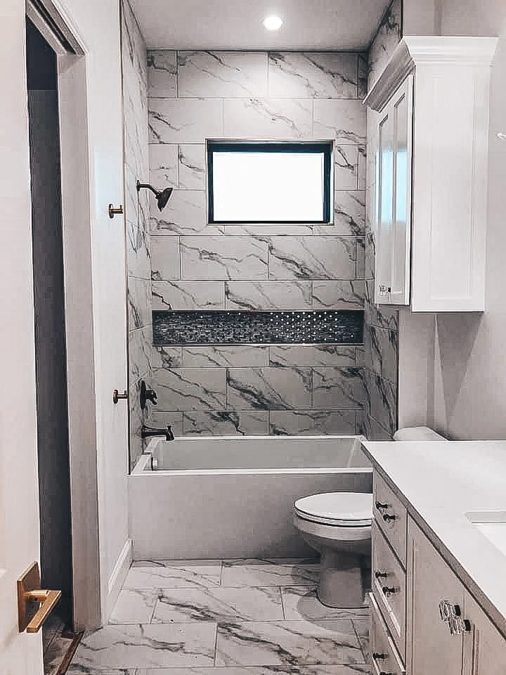 Marble tile bathroom shower with frameless glass enclosure and pebble accent strip