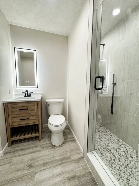 Modern bathroom with wood vanity, gray tile shower, and mosaic floor