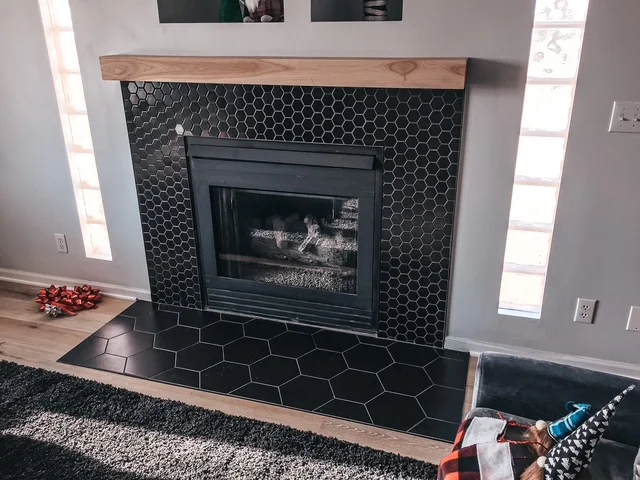 Black hexagonal tile fireplace surround with wood mantel and gas insert