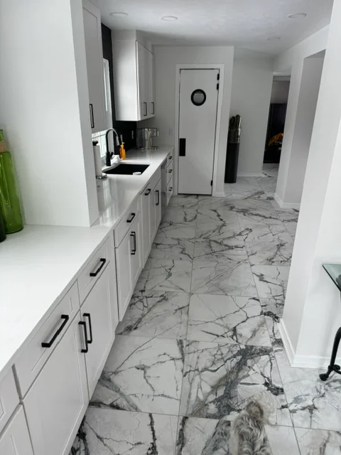 White kitchen cabinets with marble-look porcelain tile flooring and quartz countertops