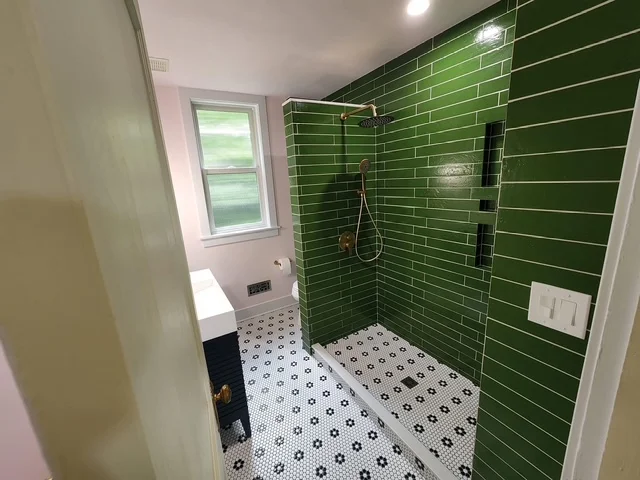 Green subway tile shower with geometric hexagonal floor tiles and frameless glass enclosure
