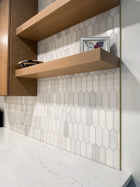 White hexagonal tile backsplash with floating wood shelves and quartz countertop