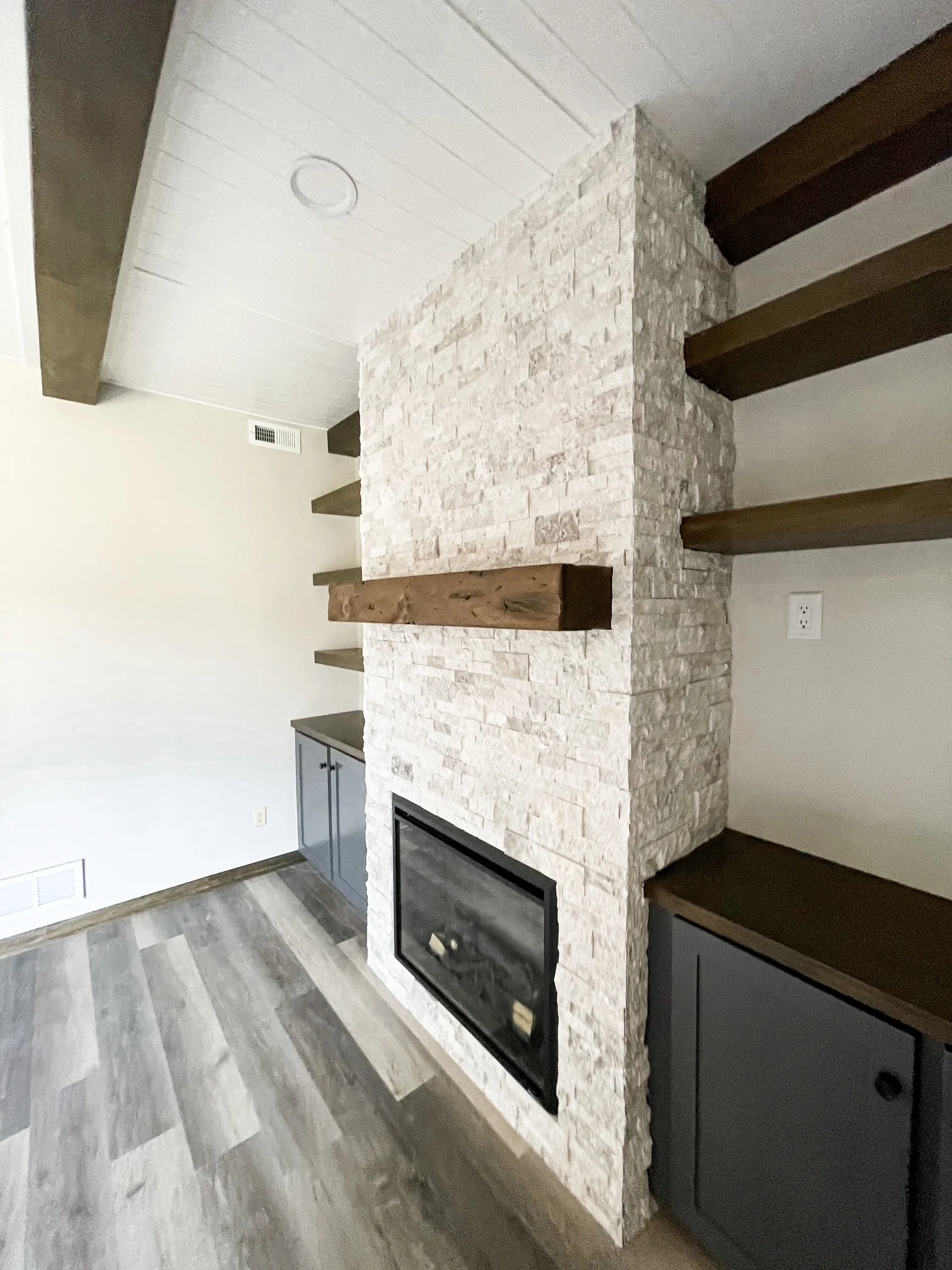 A finished custom wood fireplace surround with a built-in mantel shelf installed in a Lincoln, Nebraska living room, showing clean trim joints and a painted finish that matches the room's existing woodwork.